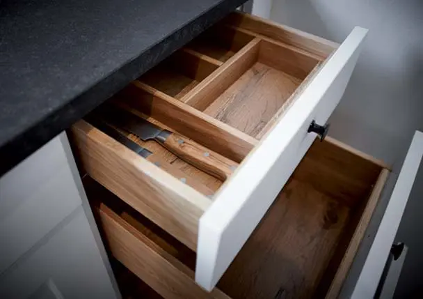 Un tiroir de cuisine avec rangement en bois et une façade blanche