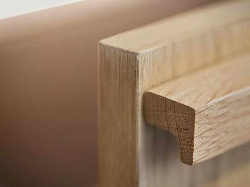 Détail d’une poignée de meuble en bois massif, aux lignes épurées et finition naturelle, illustrant la qualité artisanale du mobilier de cuisine