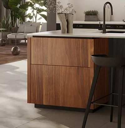 Îlot central de cuisine en bois nervuré avec plan de travail blanc, tabouret noir et vue sur un espace salon lumineux, illustrant un design moderne et chaleureux.