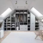 Dressing contemporain aménagé sous les combles, doté de nombreux compartiments ouverts pour vêtements, sacs et accessoires, éclairé par deux grandes fenêtres de toit.