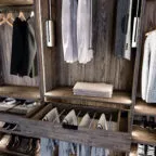 Vue d’un dressing en bois foncé équipé de penderies, d’un tiroir coulissant pour pantalons suspendus, d’étagères à chaussures et de rangements pour chemises et costumes.