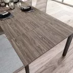 Table à manger extensible en bois foncé entièrement ouverte, offrant une grande surface continue, idéale pour accueillir plusieurs invités.