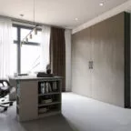 Bureau spacieux avec bibliothèque intégrée dans le meuble, grand placard à portes battantes texturées et large fenêtre habillée de rideaux, créant un environnement de travail élégant et lumineux.