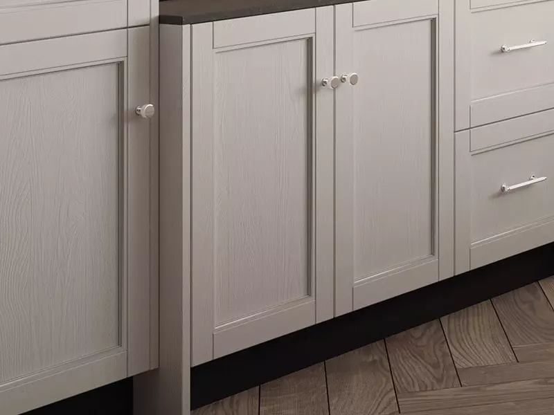 Gros plan sur les façades de placard de cuisine en bois texturé gris clair avec poignées rondes blanches, soulignant la qualité des finitions et le style contemporain.