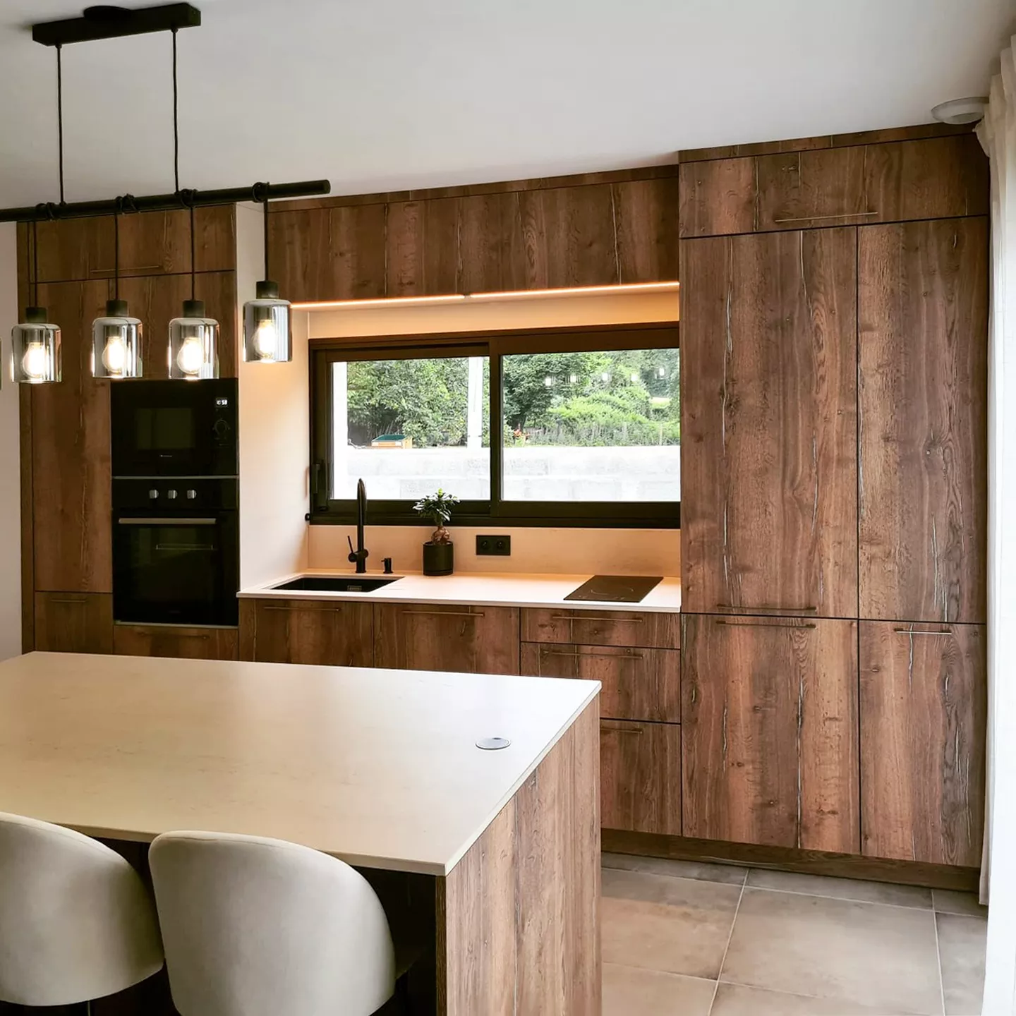 Plongez dans l’élégance d’une cuisine moderne alliant des façades en bois naturel et un îlot central spacieux. Les lignes épurées, l’éclairage suspendu et les matériaux haut de gamme créent une atmosphère chaleureuse, idéale pour cuisiner et recevoir.
