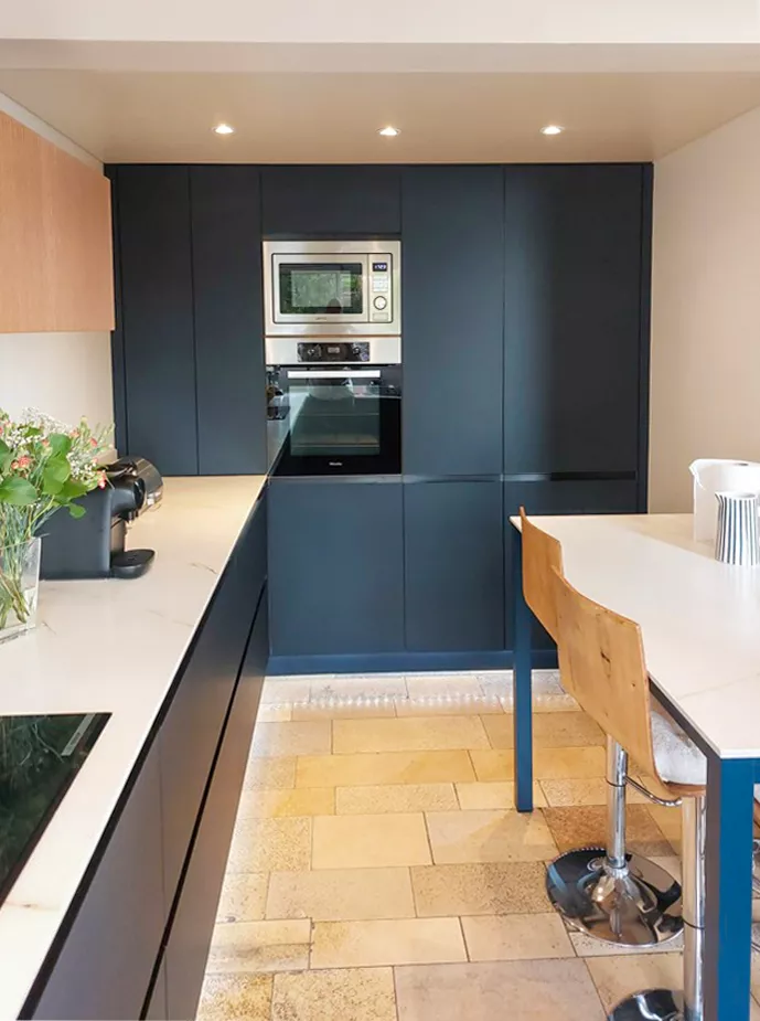 Vue sur la colonne de rangements intégrés et les appareils électroménagers encastrés dans une cuisine sur mesure au design épuré, réalisée par Cuisines Premier Plan Le Havre.