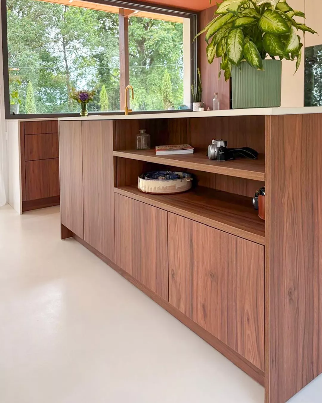 Îlot central en bois noyer avec rangements ouverts, plan de travail clair et accessoires déco, dans une cuisine sur mesure lumineuse signée Premier Plan Anglet