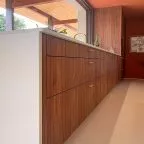 Enfilade de tiroirs en bois noyer avec poignées dorées, plan de travail clair avec rigoles d’égouttage, cuisine haut de gamme Premier Plan Anglet