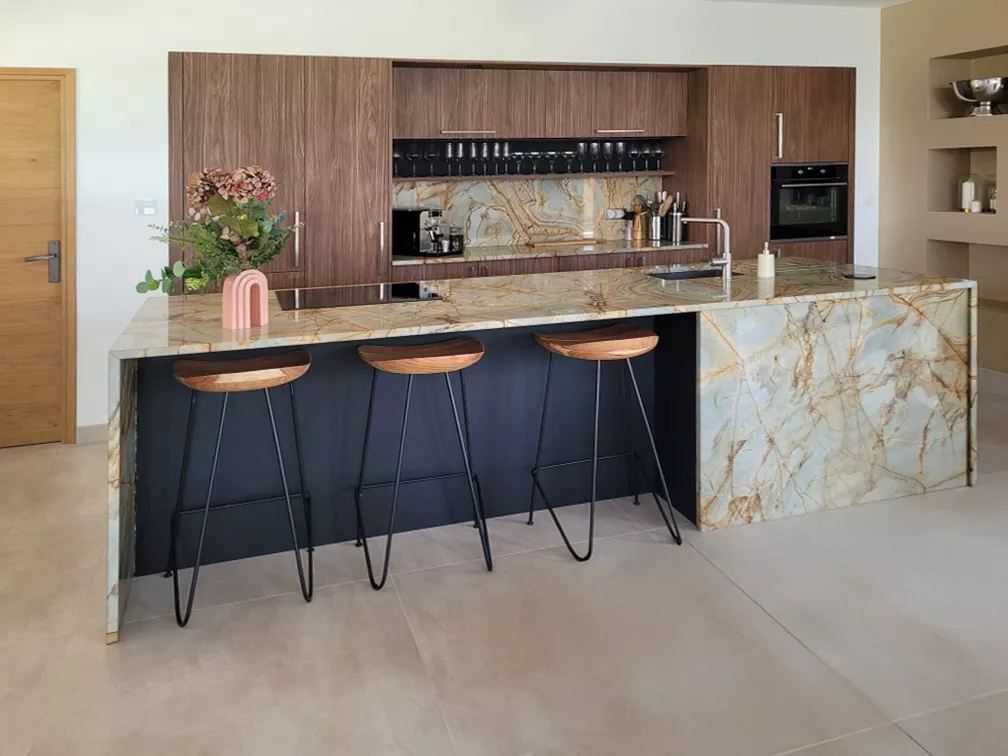 Vue de face de la cuisine avec espace bar convivial intégré à l'îlot et trois tabourets style industriel bois et métal.