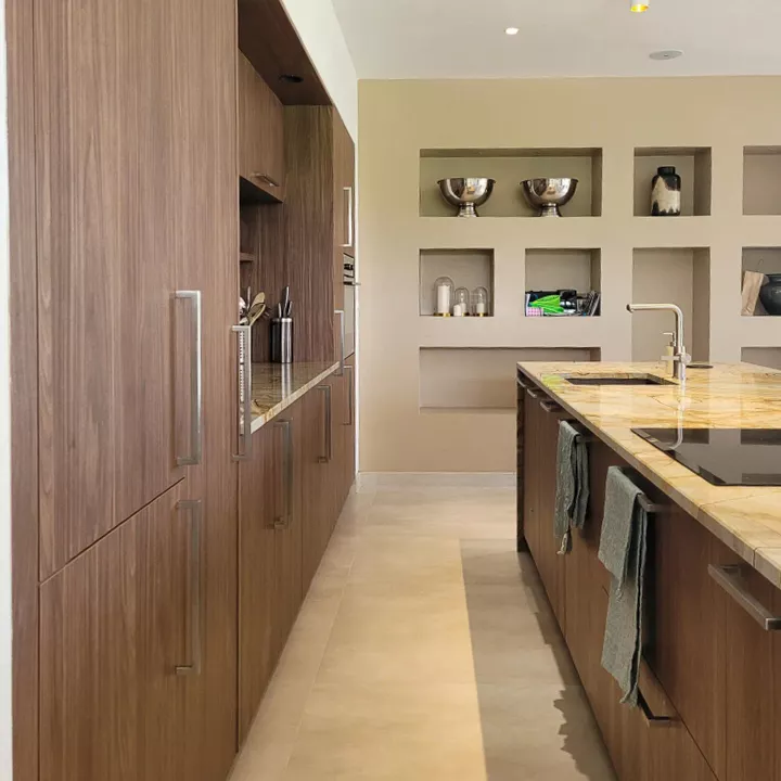 Couloir de circulation entre l'îlot et les armoires toute hauteur en bois décor Rotpunkt City Oak Brown.