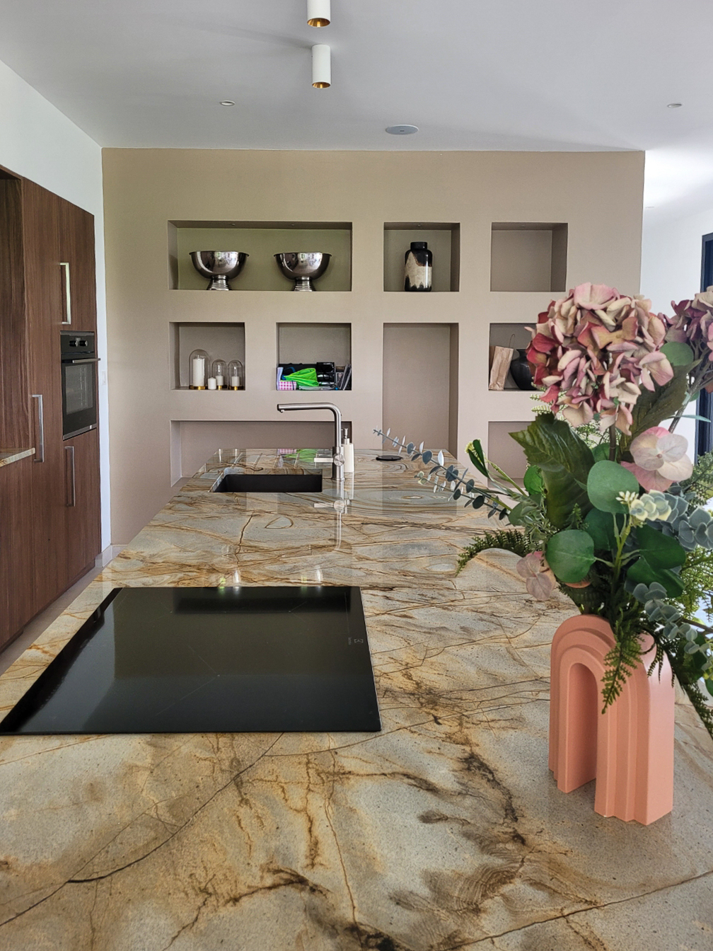 Gros plan sur la texture du granit et la décoration, mettant en valeur le contraste entre la pierre froide et les accessoires colorés.