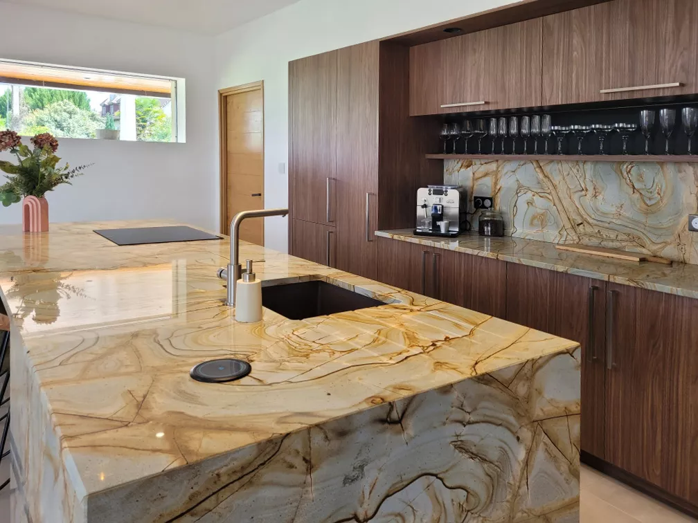 Zoom sur le plan de travail en granit Emperator avec évier sous plan et robinetterie inox, face à une niche décorative bois.