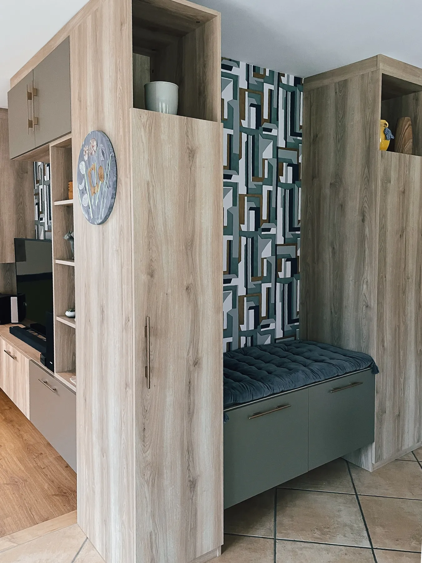 Rangement d’entrée sur mesure avec banquette, placards toute hauteur, niches décoratives et façades vert grisé.