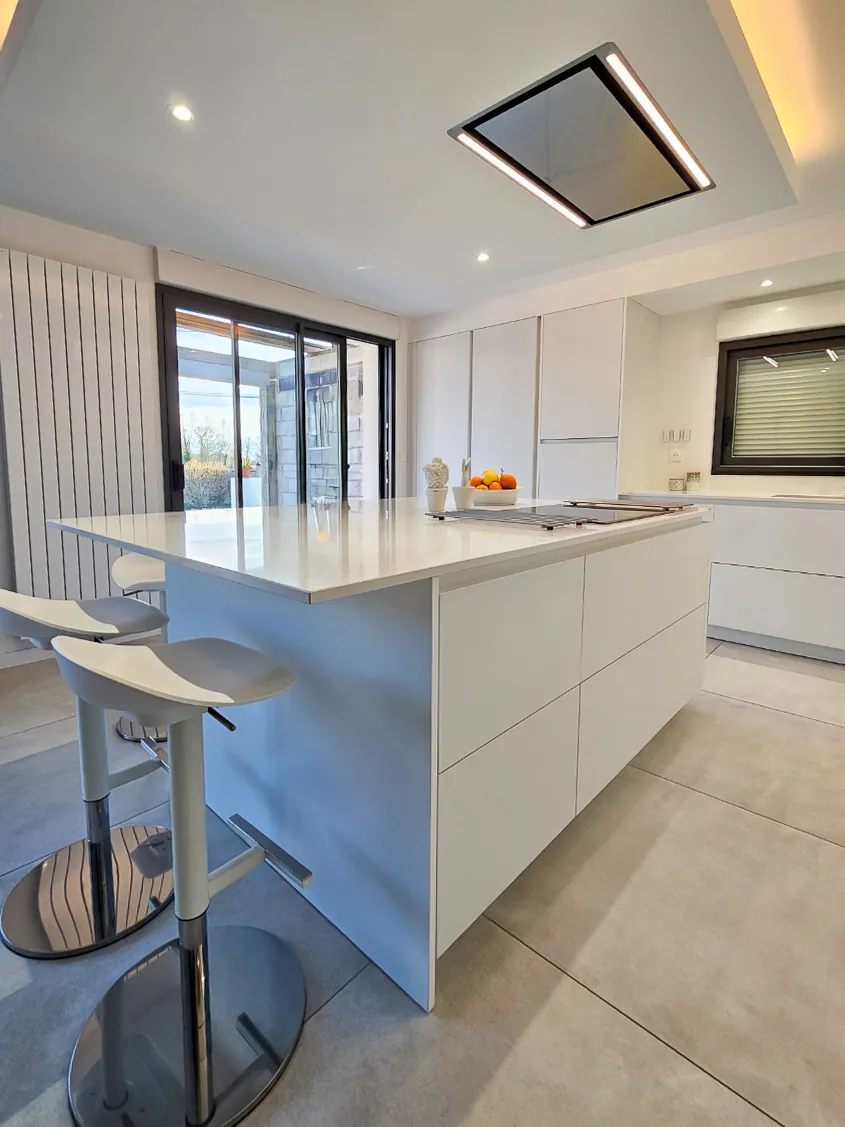 Aménagement d'une cuisine blanche en laque mate avec îlot central en quartz Calacatta Gold et mur d'armoires toute hauteur