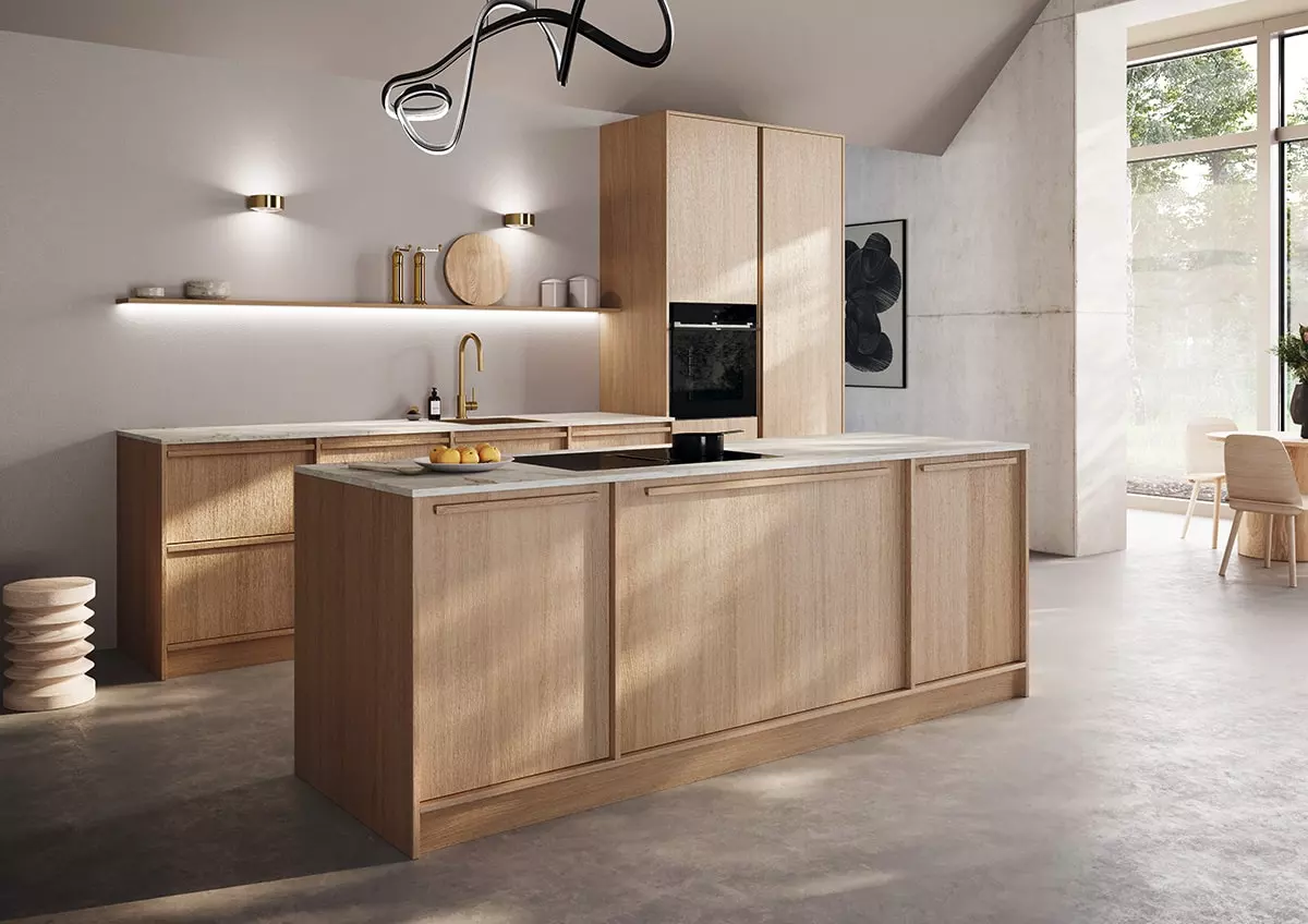 Cuisine Rotpunkt en bois clair avec îlot central, four encastré, plan de travail clair et éclairage mural.