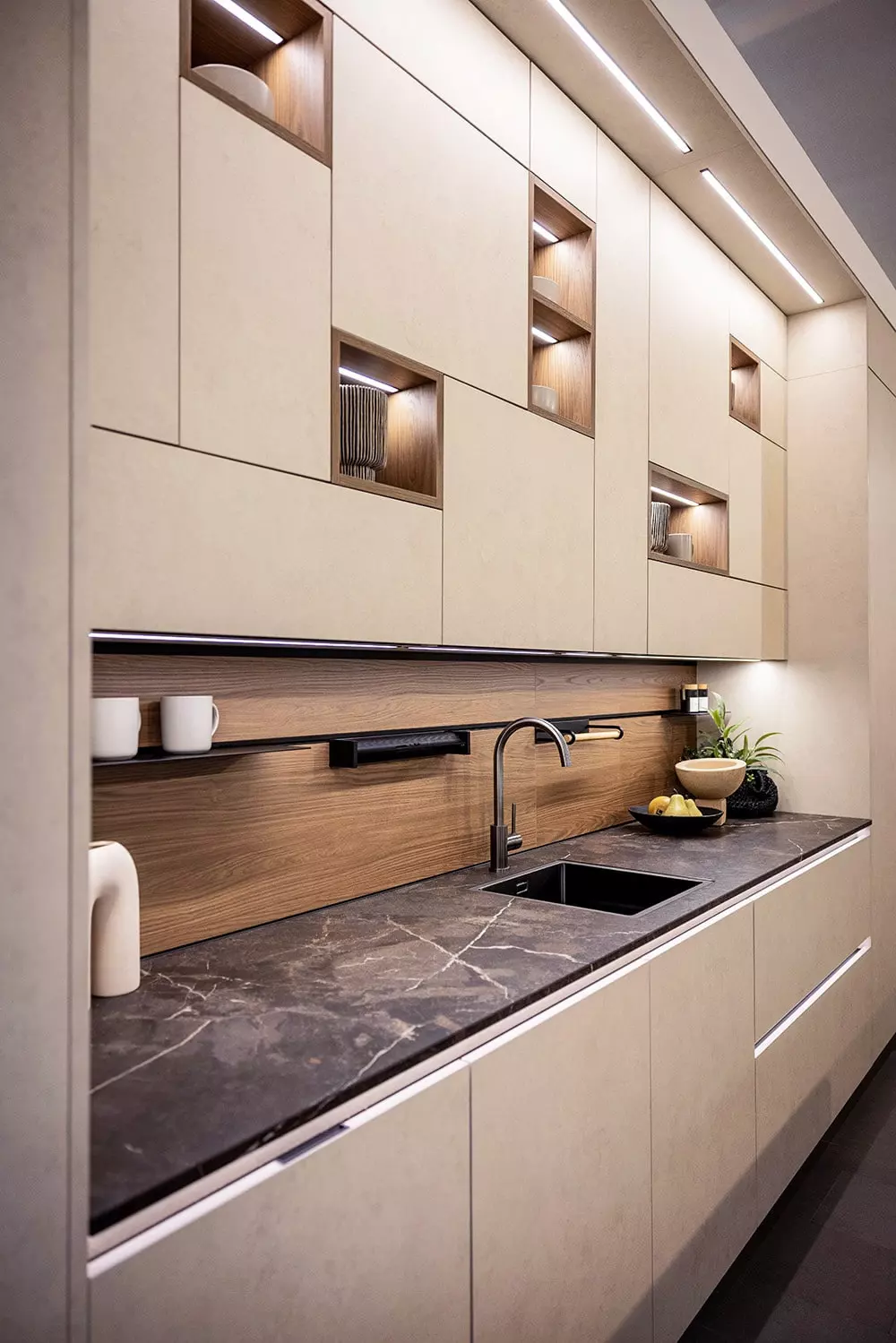 Cuisine Rotpunkt design avec façades claires, niches ouvertes décor bois, plan de travail foncé et éclairage intégré.