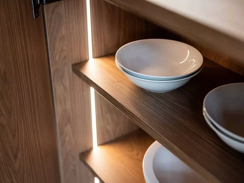 Étagères en bois avec éclairage intégré pour ranger la vaisselle dans une cuisine contemporaine haut de gamme.