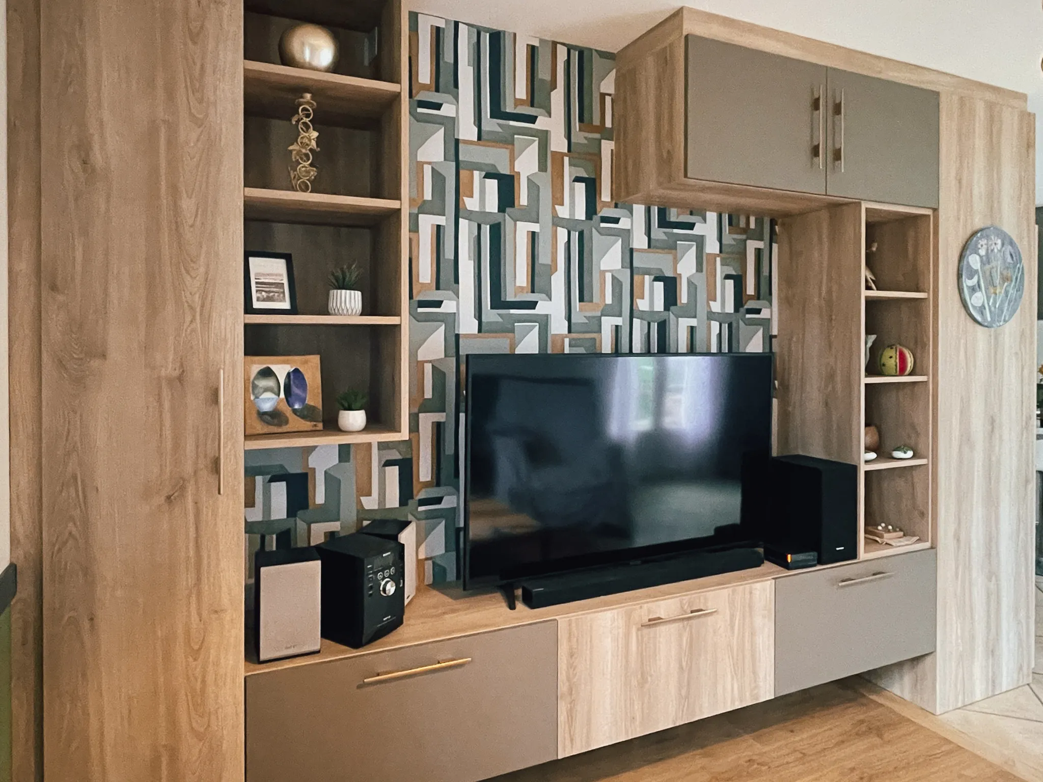 Meuble TV sur mesure Premier Plan avec rangements fermés, niches décoratives et papier peint graphique en fond mural.