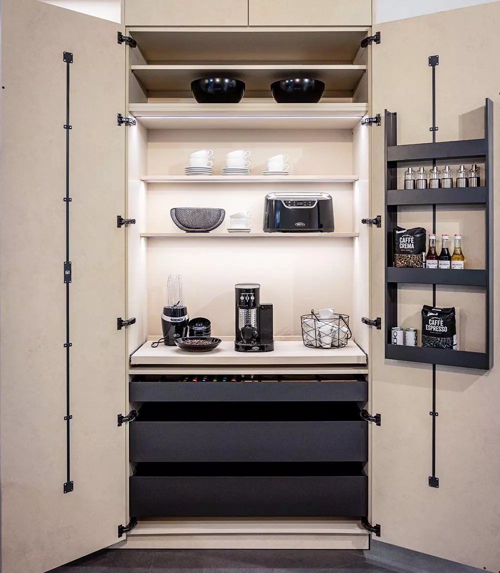 Meuble de cuisine ouvert avec espace café, étagères éclairées, grands tiroirs et rangements intégrés dans les portes.