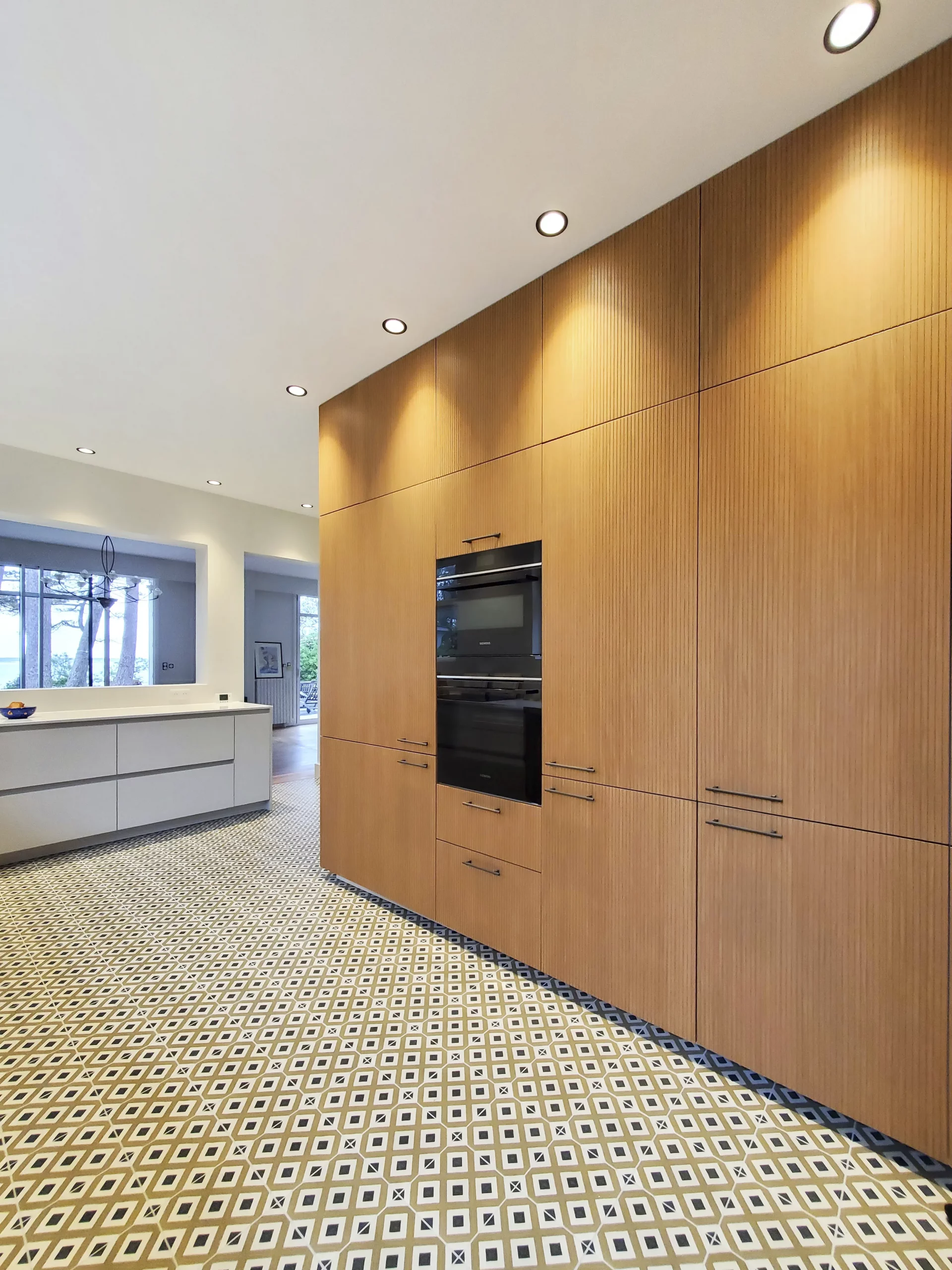 Cuisine sur-mesure Premier Plan Montauban avec grandes colonnes en bois rainuré, électroménager intégré et sol carreaux à motifs
