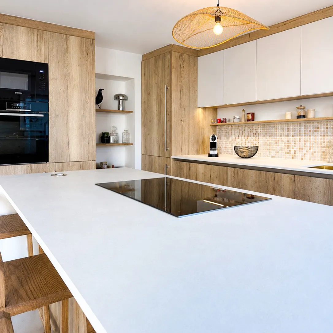 Cuisine sur-mesure Premier Plan Longlaville avec grand îlot blanc, meubles bois, crédence mosaïque et suspension en fibre naturelle