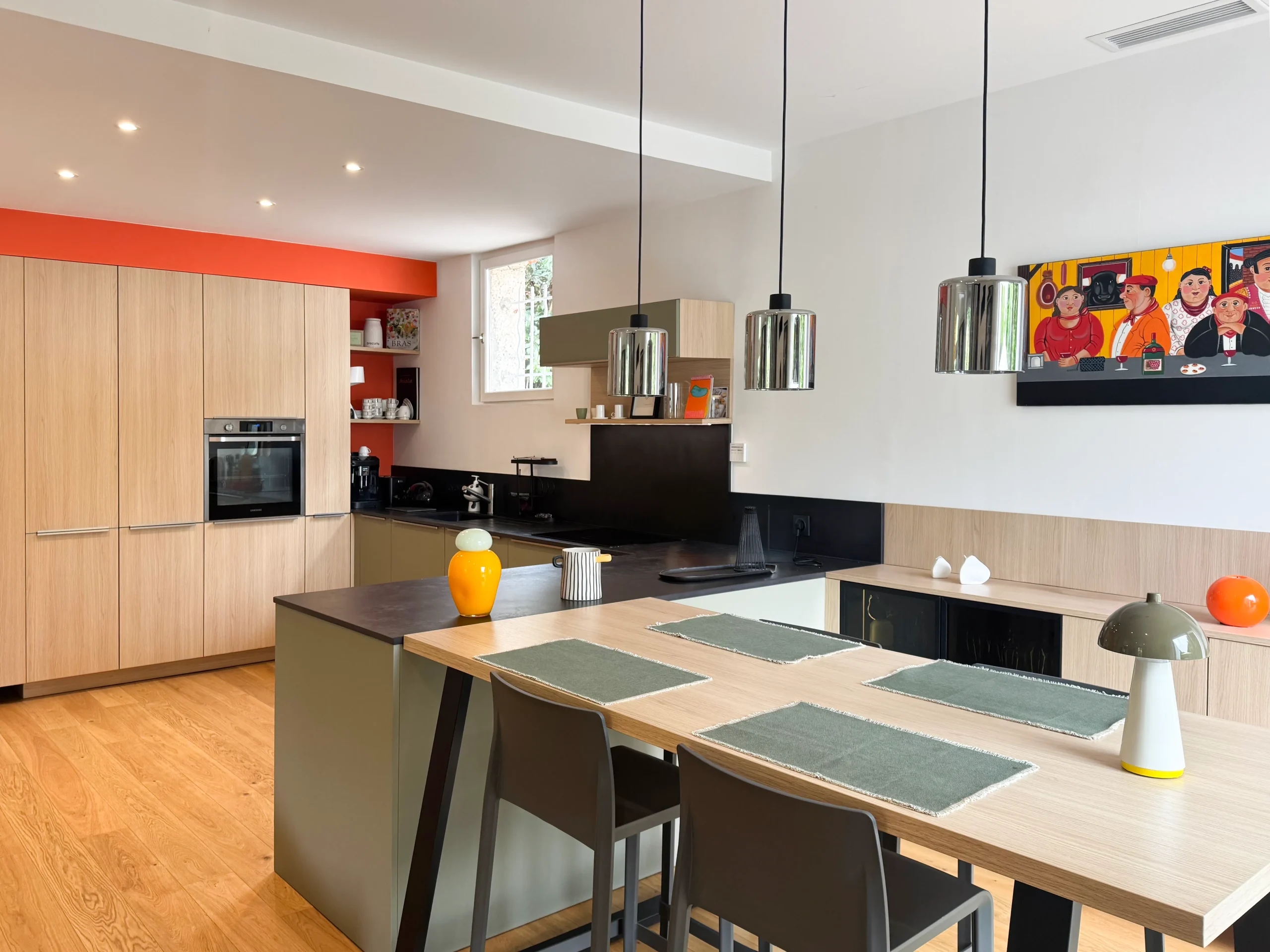 Cuisine contemporaine Premier Plan Carbonne associant colonnes en bois clair, façades grèges, plan de travail noir et table repas attenante